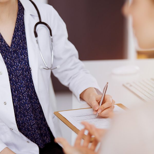 Doctor and patient discussing current health examination while sitting in sunny clinic. Perfect medical service in hospital.