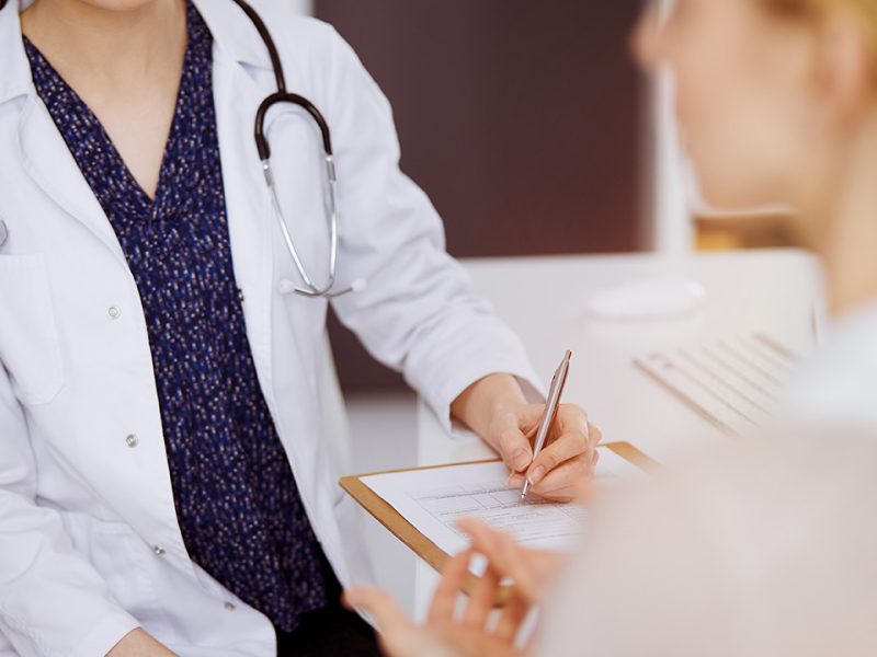 Doctor and patient discussing current health examination while sitting in sunny clinic. Perfect medical service in hospital.